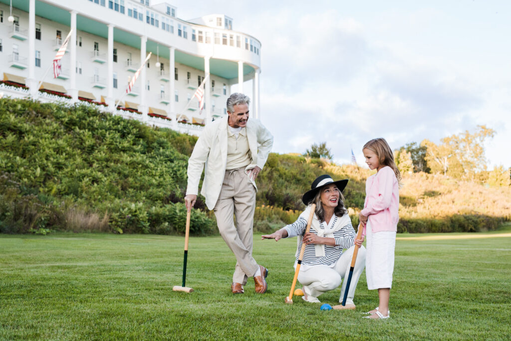 Photo of an older coupld and grand child teaching croquet - The Grand Hotel Hospitality Marketing