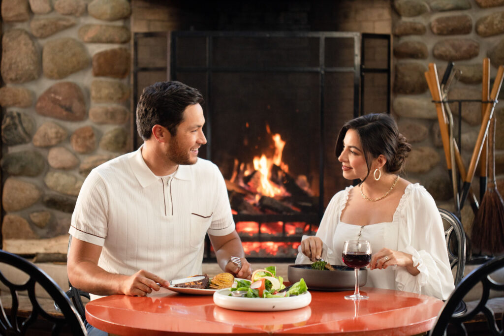 A young couple having a nice dinner by a fire in an upscale hotel - The Grand Hotel Hospitality Marketing