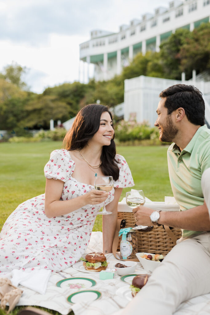 A young couple having a nice picnic with wine on the lawn of an upscale hotel - The Grand Hotel Hospitality Marketing