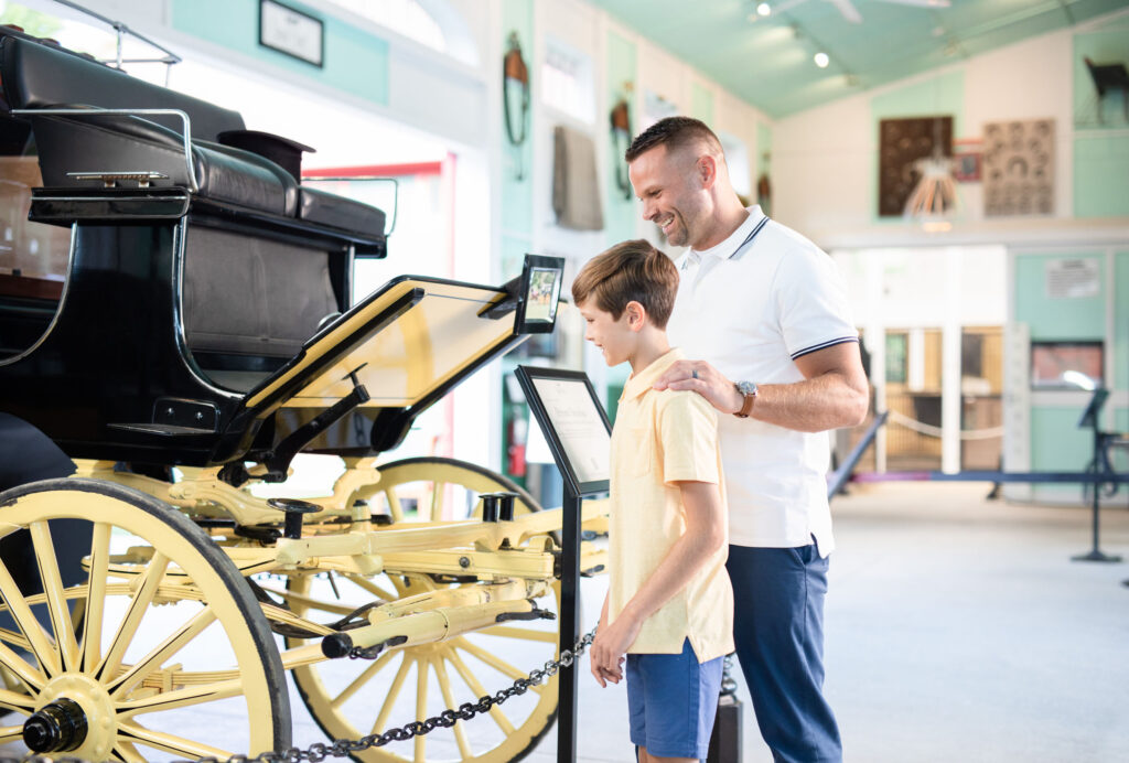 A father and son ejoying a carriage museum display - The Grand Hotel Hospitality Marketing