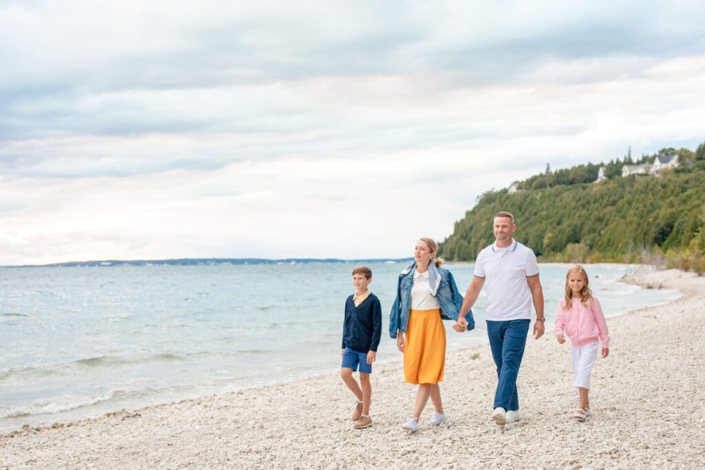 A family of four at walking on the beach of Mackinac island - The Grand Hotel Hospitality Marketing