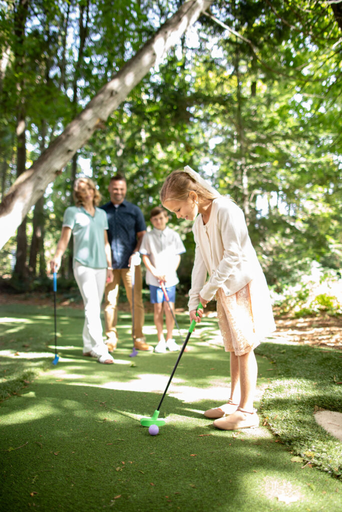 A family of four at putt-putt watching daughter putt - The Grand Hotel Hospitality Marketing