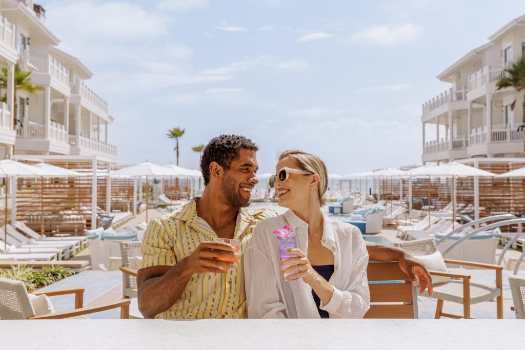 A young couple sitting by hotel pool with a cocktail Hotel Photography - Shore House at the Del