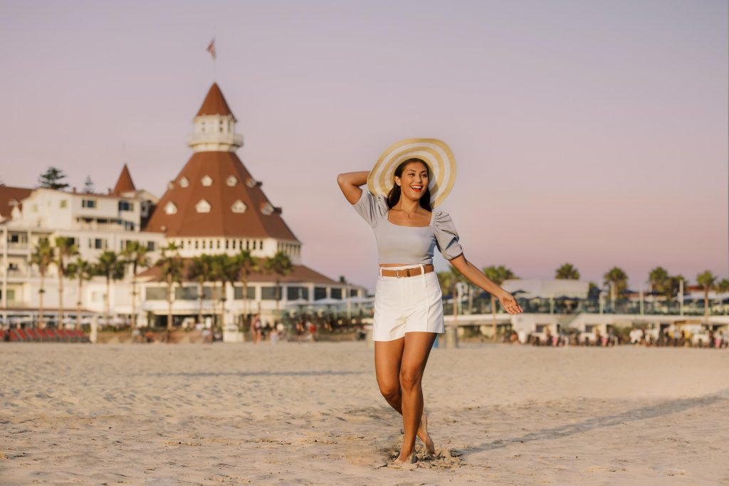 A young woman walking on a hotel beach at dusk - sun hat - Hotel Photography - Shore House at the Del