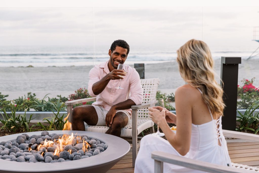 A young couple laughing at the beach with wine. Hotel Photography - Shore House at the Del