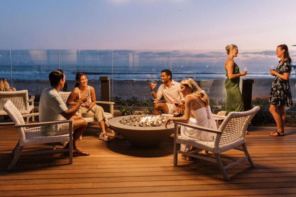 A group of young couples and friends at a beach side fire Hotel Photography - Shore House at the Del