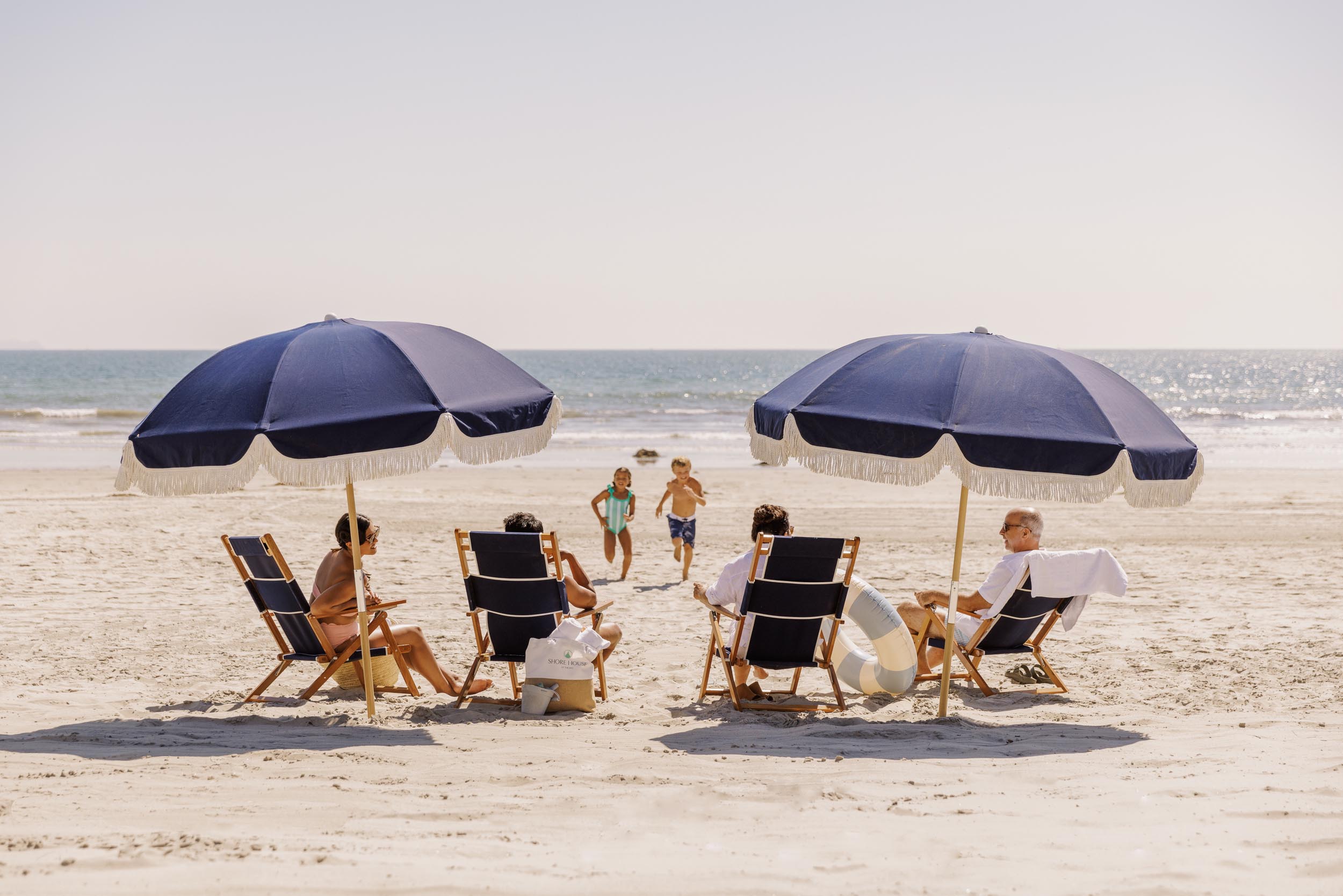 A young family watching two children run on the beach - Hotel Photography - Shore House at the Del